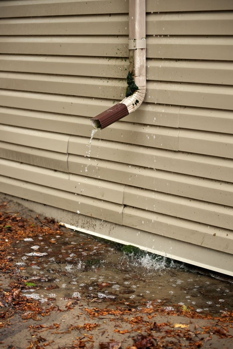 Short downspout emptying rainwater right at the foundation