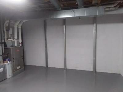 Three vertical steel I-beams braced against a painted block basement wall in the utility room