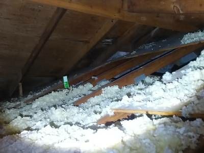 Darkened, discoloured roof sheathing between rafters seen from inside the attic